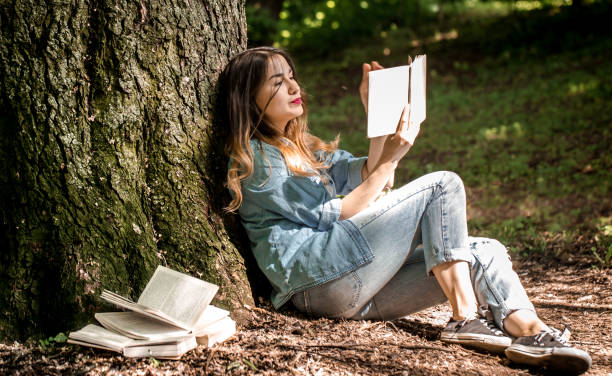 istock Girl reading a book near a tree 692465238