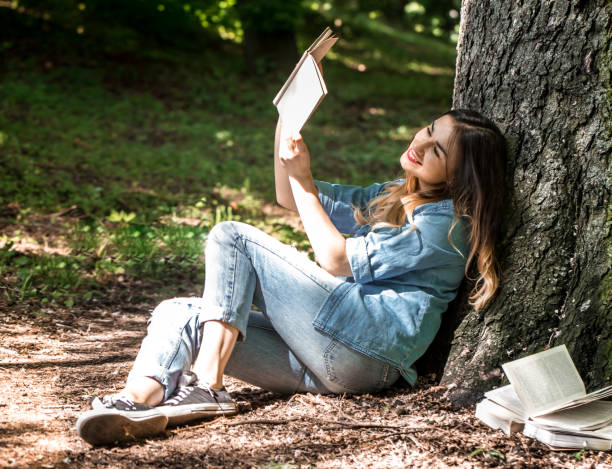 istock Girl reading a book near a tree 692465244