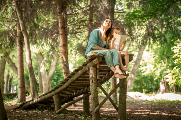 istock mother and daughter read a book in the park 692465264