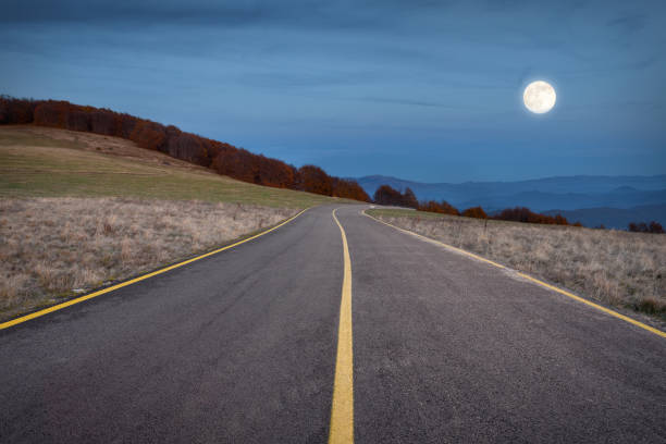 istock Driving on winding road towards the super moon at night 692465506