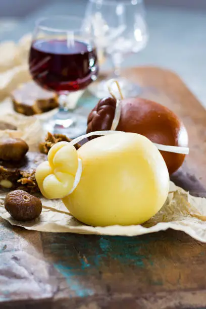 Sicilian sweet dessert liqueur wine Marsala in glass, hard cheese Caciocavallo or Provolone, dried figs with figs bread, still life on wooden table