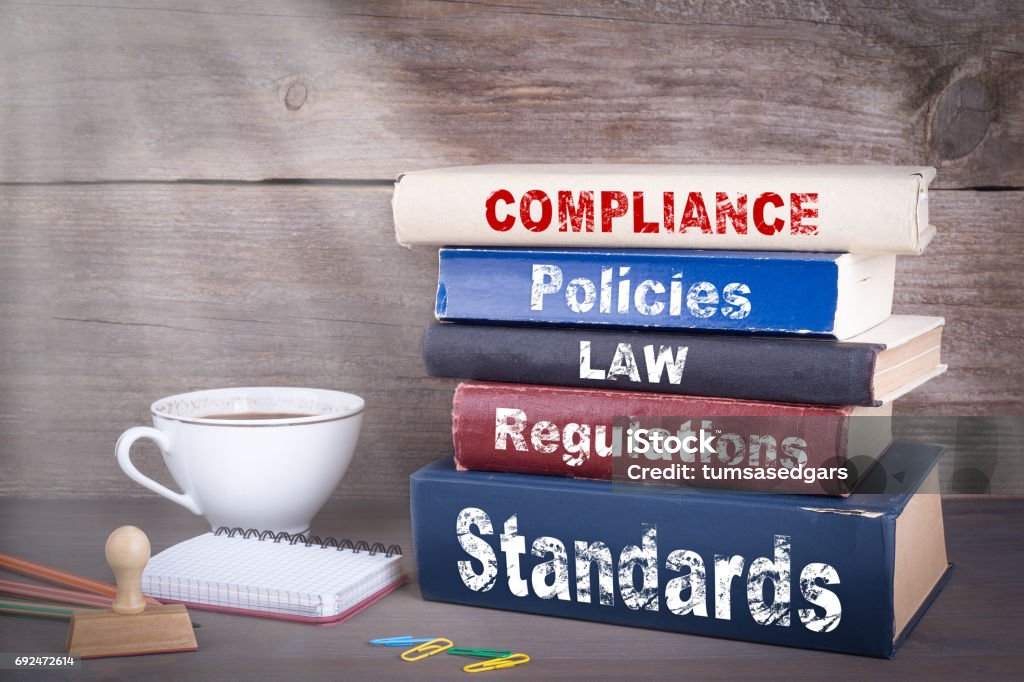 Compliance concept. Stack of books on wooden desk Law Stock Photo