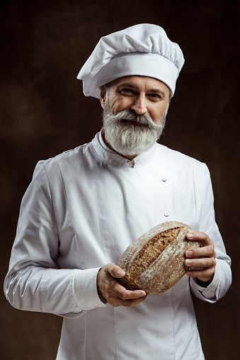 Baker holding fresh bread. Bakery.