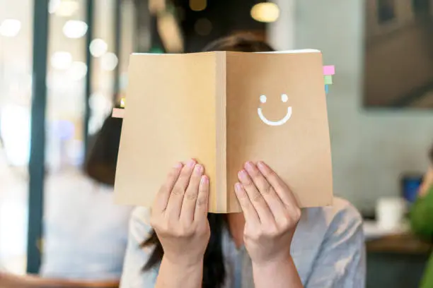 Photo of girl holding book covering face