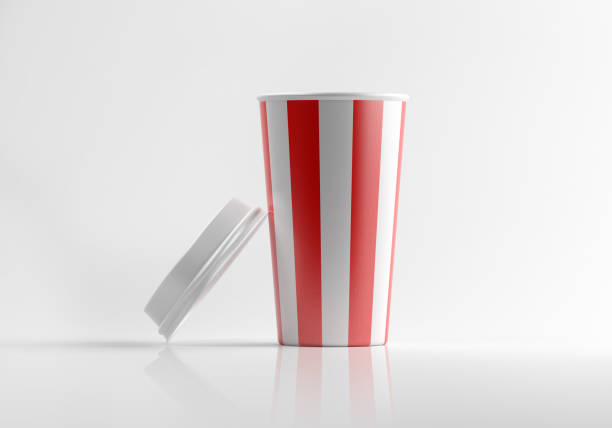 A red and white striped generic paper insulated soda cup with lid side by side on a white reflective surface. Lit from upper right corner and casting soft shadows on the ground. Clipping path for coffee cup is included. Horizontal composition with copy space.
