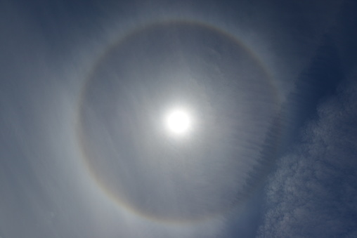 Also known as the 22 degree halo your position in relation to the Sun, caused by water droplets high up in Cirrus clouds in a clear sky usually predict storms closeby.