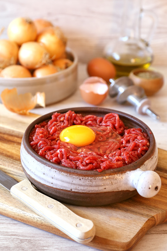 Raw minced meat, eggs, olive oil, onions and detail of meat grinder