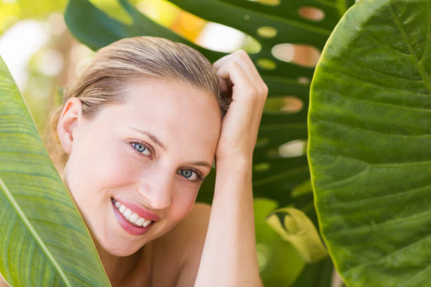 istock Beautiful blonde smiling at camera behind leaf 692530116