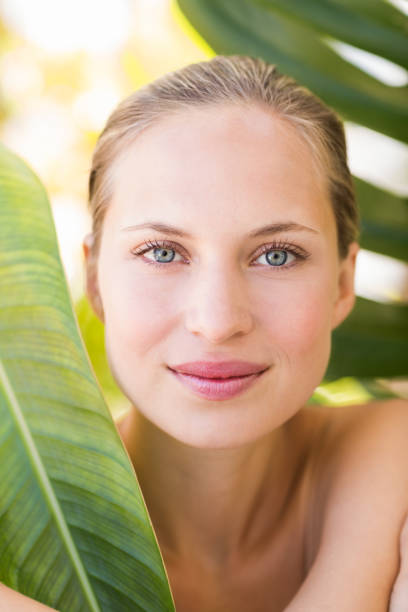 istock Beautiful blonde smiling at camera behind leaf 692530302