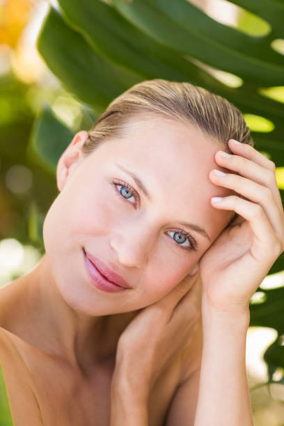 istock Beautiful blonde smiling at camera behind leaf 692530508