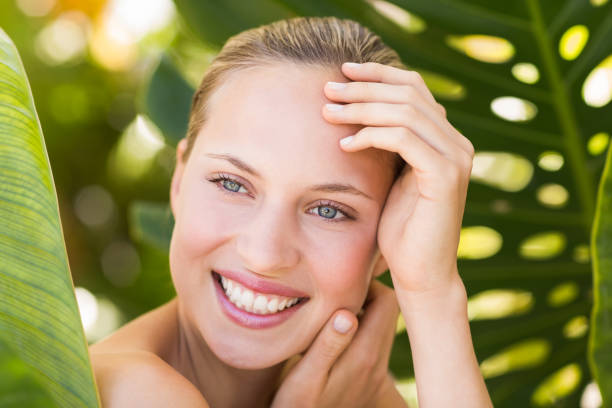 istock Beautiful blonde smiling at camera behind leaf 692530564