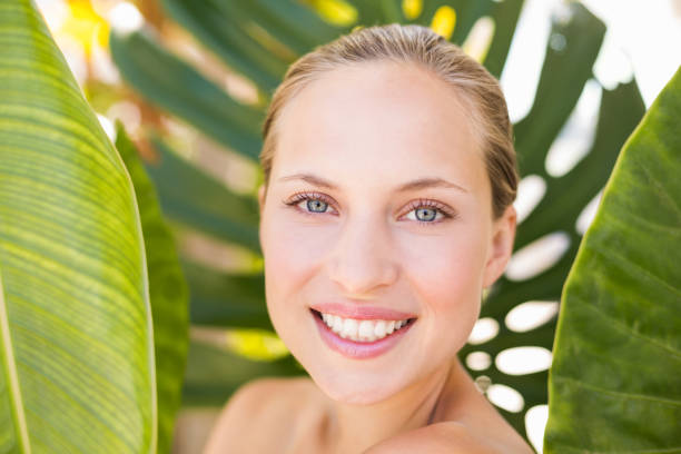 istock Beautiful blonde smiling at camera behind leaf 692532810