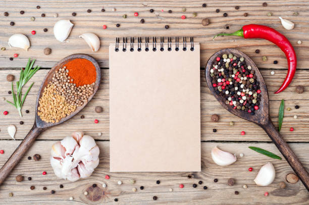 istock Spices background with copy space. Open blank notebook, rosemary, pepper, paprika, fenugreek, coriander, chilli and garlic on wooden background 692545890