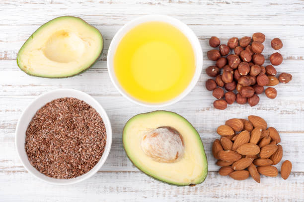 alimentos con grasas saludables. fuentes de omega 3 - aguacate, aceite de oliva, nueces y semillas de lino sobre fondo de madera. concepto de comida sana. vista superior - fat fotografías e imágenes de stock