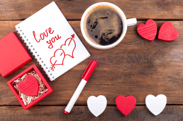 istock Romantic I love you note on notepad, coffee cup and decorative hearts on old wooden background. Romantic present. Valentines day background 692553056