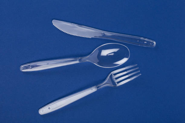 istock Transparent plastic cutlery. Knife, fork, spoon on blue paper background 692553156