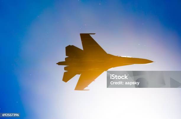 Silhouette Of A Military Fighter Sun Lights Blue Sky Stock Photo - Download Image Now