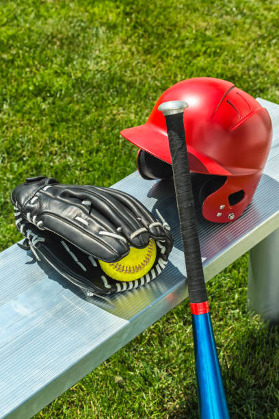 yellow softball in glove with bat and helmet on bench - softball playing field fluorescent team sport imagens e fotografias de stock