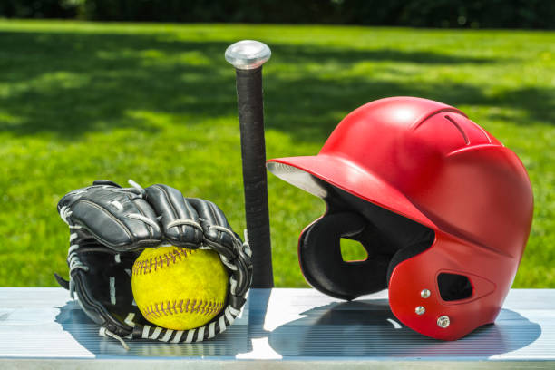 yellow softball in glove with bat and helmet on bench - softball playing field fluorescent team sport imagens e fotografias de stock