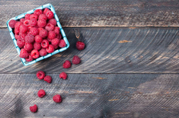 Raspberries in a basket on old wooden background. Summer berries. Rustic style. Top view