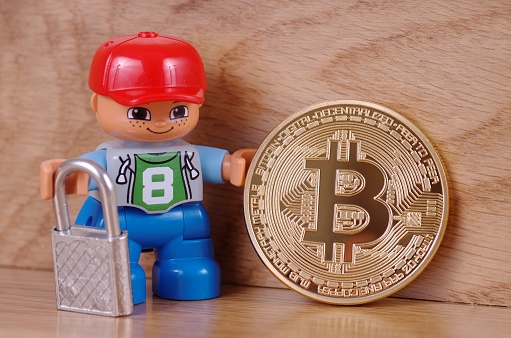 Saransk, Russia - June 03, 2017: Lego man hold Bitcoin and padlock on the hands. Bitcoin is a most popular cryptocurrency and a digital payment system.