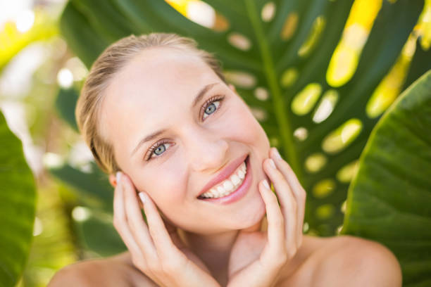 istock Beautiful blonde smiling at camera behind leaf 692567174