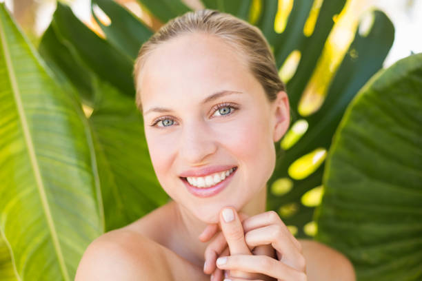 istock Beautiful blonde smiling at camera behind leaf 692567554