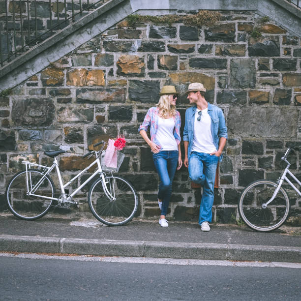 istock Hip young couple standing by brick wall with their bikes 692573262