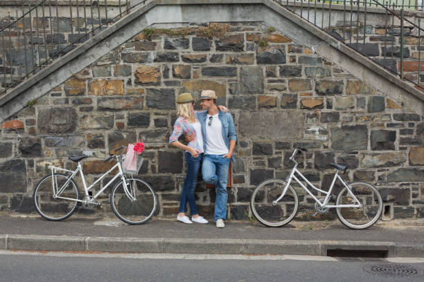 istock Hip young couple standing by brick wall with their bikes 692573404