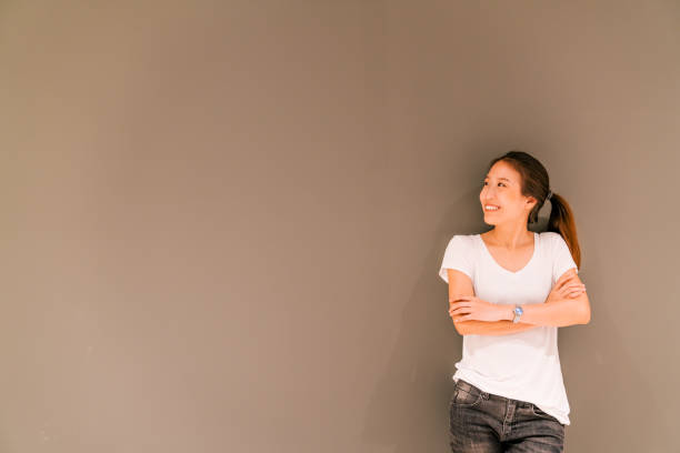istock Beautiful Asian girl standing on grey wall background, looking at copy space 692576676