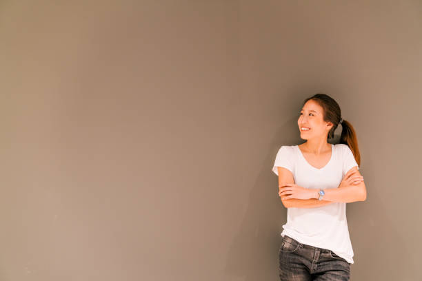 piękna azjatycka dziewczyna stojąca na szarym tle ściany, patrząc na przestrzeń kopiowania - thinking women looking up businesswoman zdjęcia i obrazy z banku zdjęć
