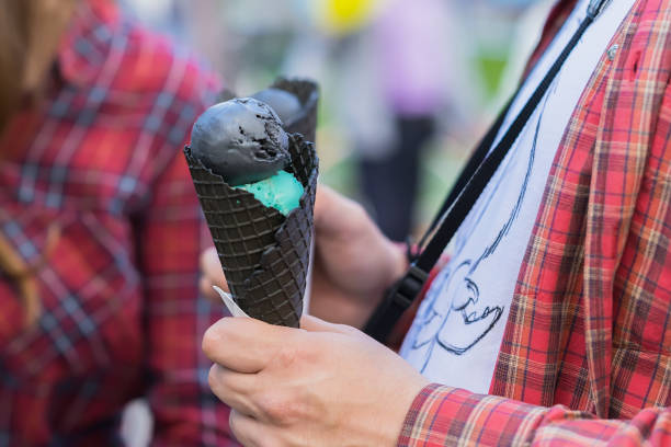 Close-up of Hands young man holding two Delicious ice-cream in black waffle cone for himself and girl, in same red shirts. Concept of love, caring, sweets, lifestyle
