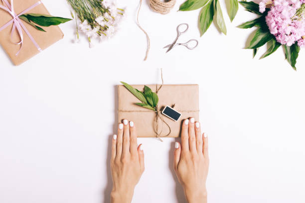 istock Festive composition, female hands wrapping a book for a gift 692578316