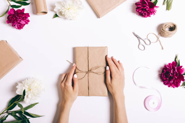istock Women's hands are packaged holiday gifts on a white background 692578334