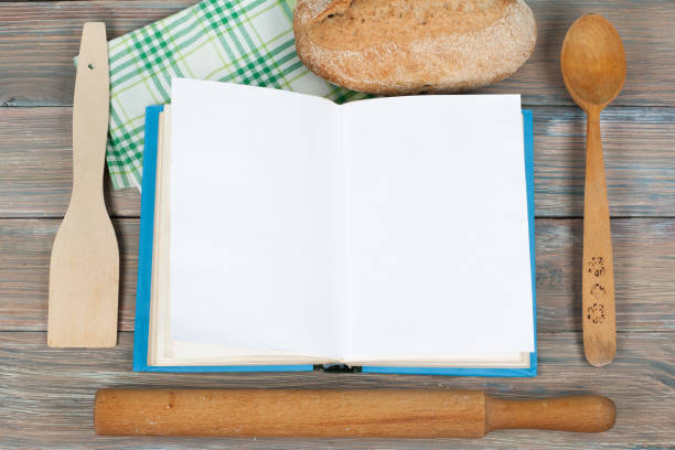 istock Open recipe book on wooden background, spoon, rolling pin , green checkered tablecloth 692580988