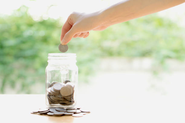 istock Woman Dropping Coins Into Glass Jar 692589912