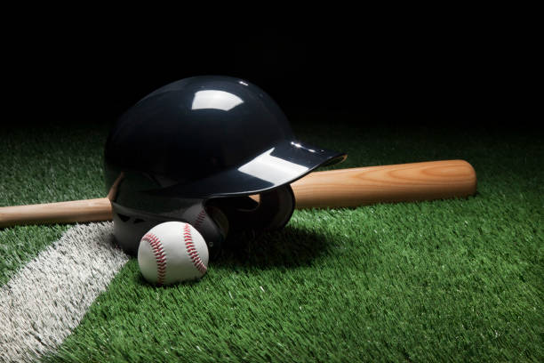 istock Baseball batting helmet bat and ball on green field 692591176