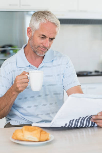 istock Happy man reading the newspaper at breakfast 692594446