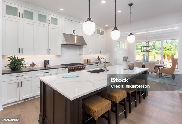 Beautiful Kitchen In New Luxury Home With Island Pendant Lights And Hardwood Floors Includes View Of Dining Room Stock Photo - Download Image Now