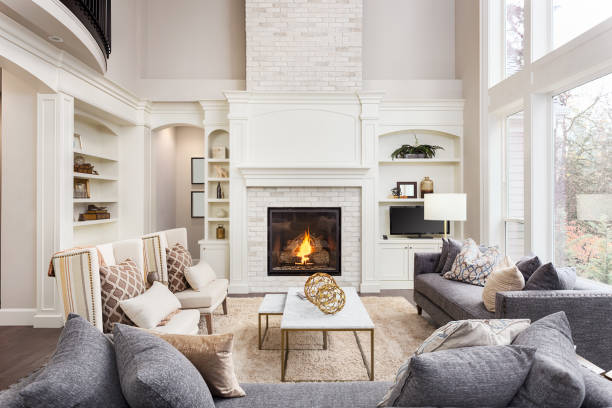 Beautiful living room interior with tall vaulted ceiling, loft area, hardwood floors and fireplace in new luxury home. Has large bank of windows living room in newly constructed luxury home renovation photos stock pictures, royalty-free photos & images