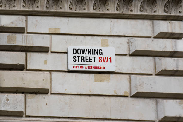 Downing Street Sign Attached to Wall by the Gates into Downing Street in Westminster, London. stock photo