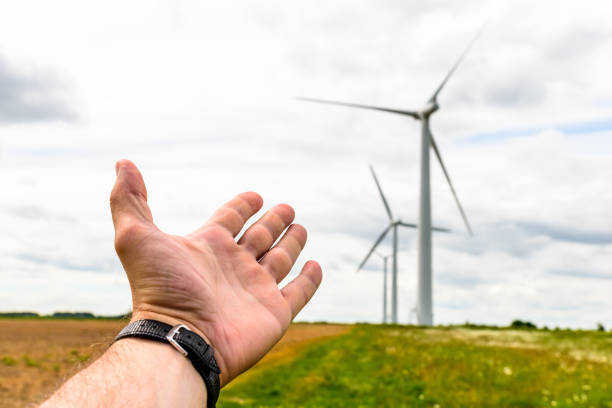 istock Human hand aiming to wind power turbines generate electricity 692622542