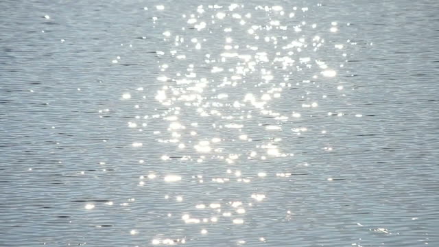 Sun path on light blue water with golden sunny bokeh circles