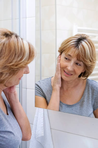istock Mature woman examining her face in the mirror 692631270