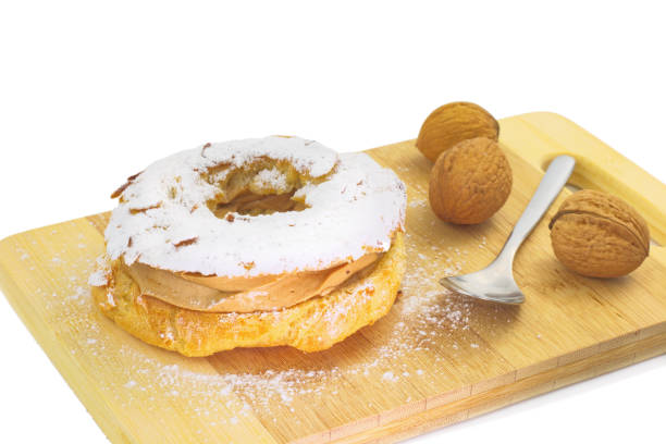 istock Paris Brest (French dessert choux pastry and praline cream) on wood board and walnuts on white background 692631698