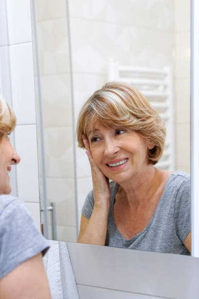 istock Mature woman examining her face in the mirror 692632078
