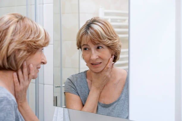 istock Mature woman examining her face in the mirror 692632146