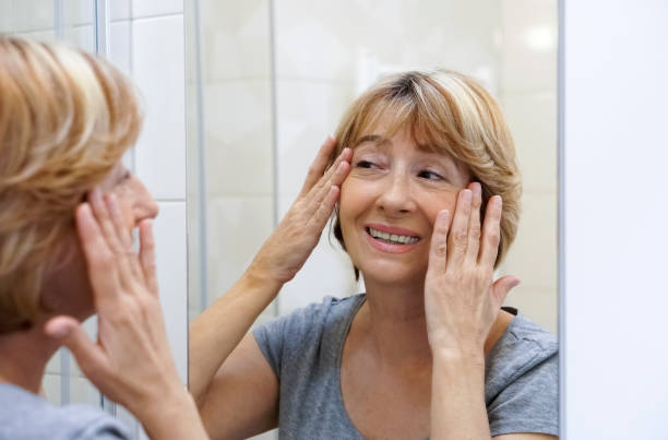 istock Mature woman examining her face in the mirror 692635504