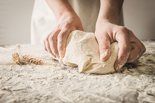 view on tasty freshly baked sourdough bread in bakery form which female hands holds. Homemade bread food photography.