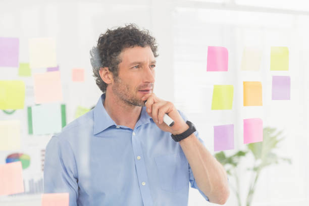 istock Puzzled businessman looking post its on the wall 692654762